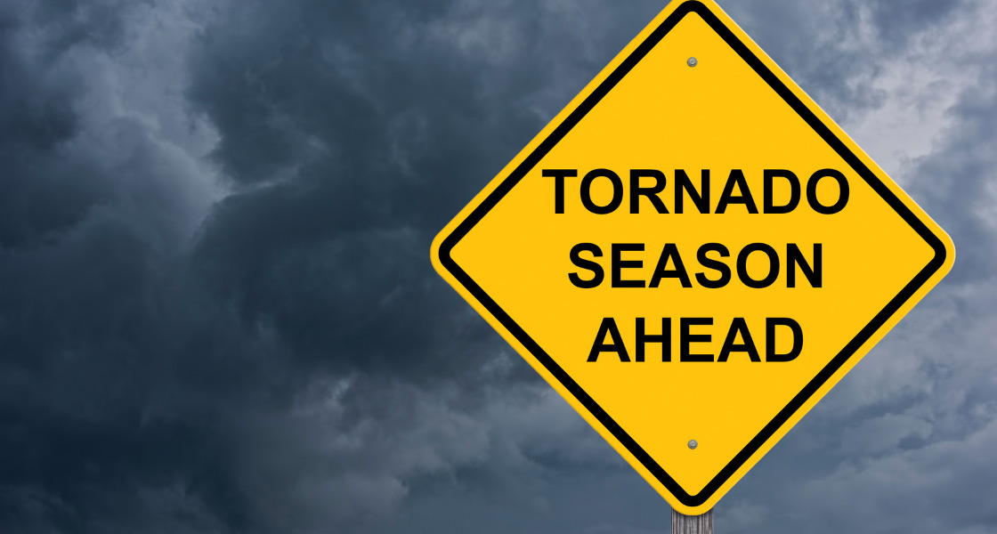 A cloudy, gray sky, is in the background. The yellow sign has the words "Tornado Season Ahead"