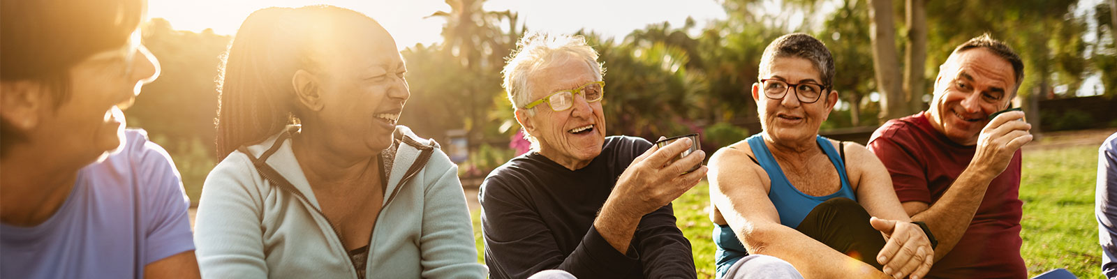 five seniors sitting outside on the lawn laughing in the sun