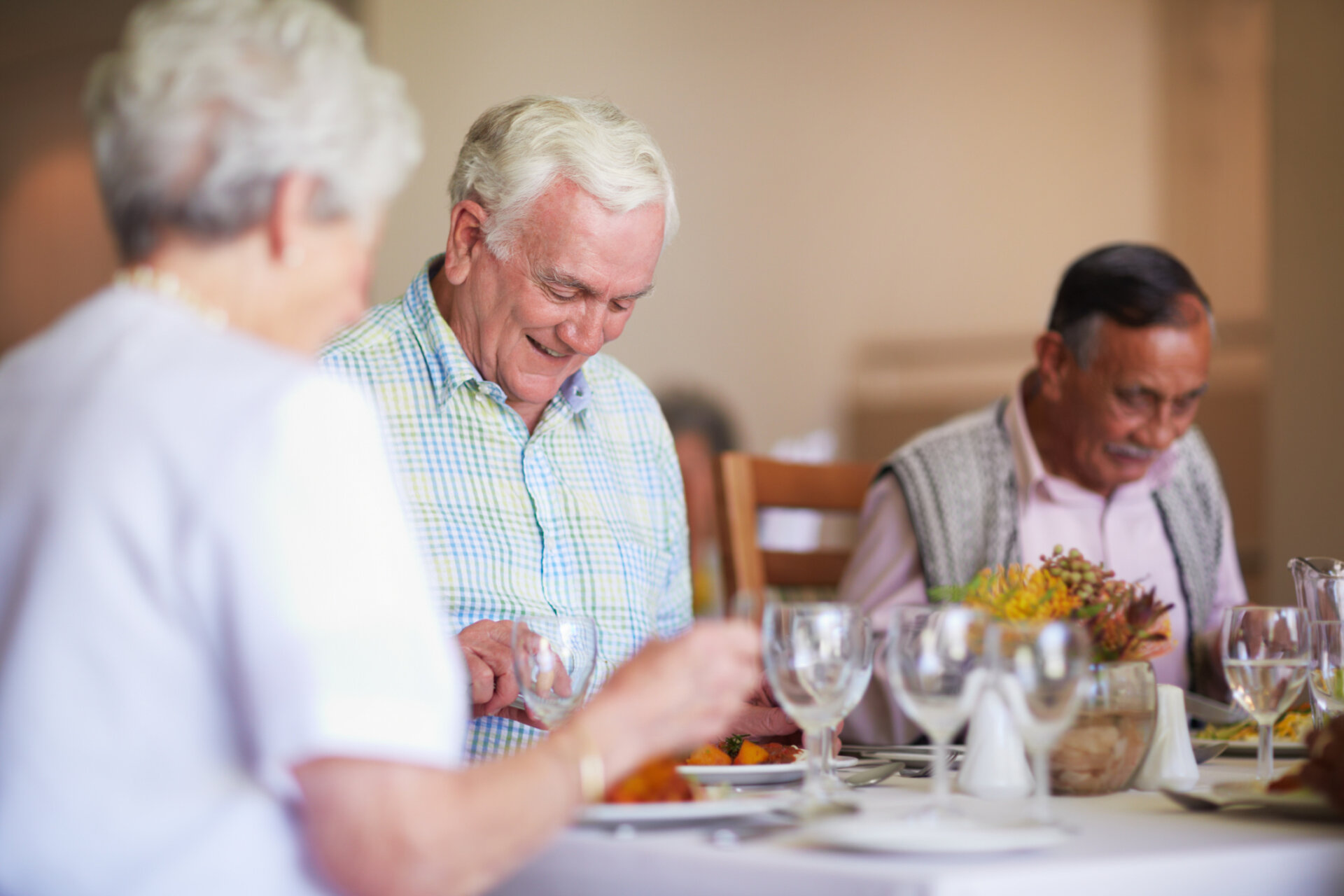 Senior living residents sitting in the dining room at a table eating a meal